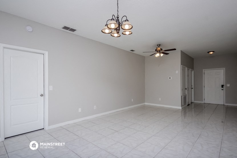an empty living room with a ceiling fan and a door to a closet
