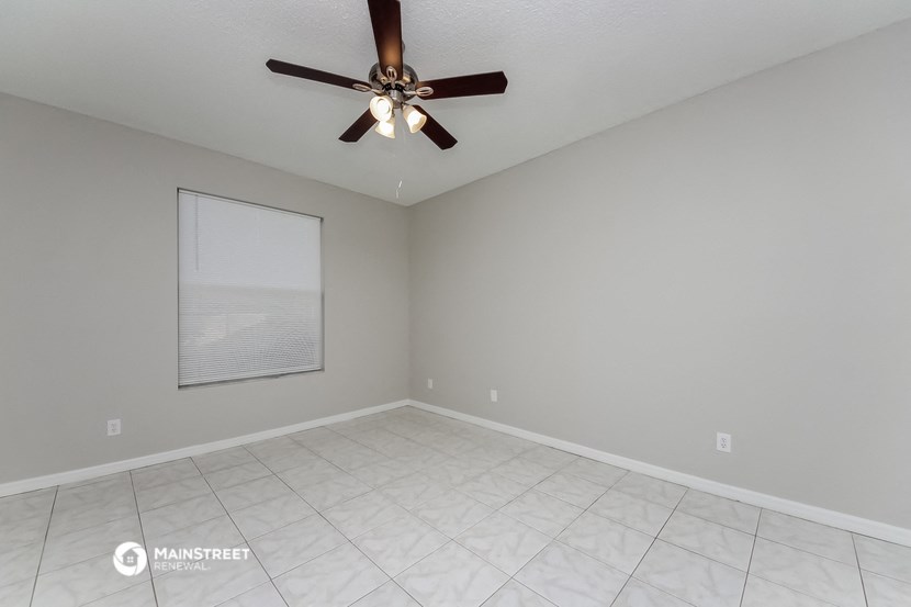 the spacious living room with ceiling fan and tile flooring