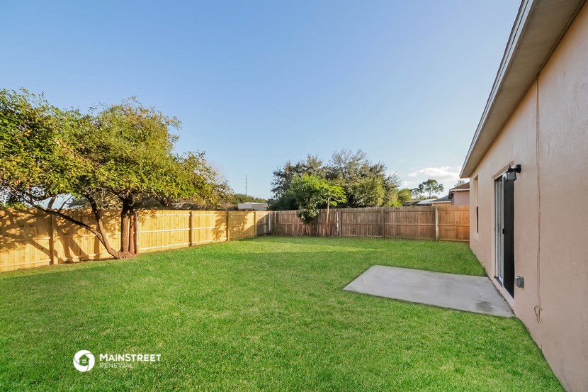 a backyard with green grass and a fence and a patio