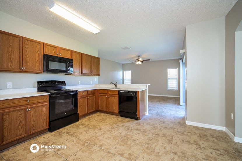 an empty kitchen with wood cabinets and black appliances