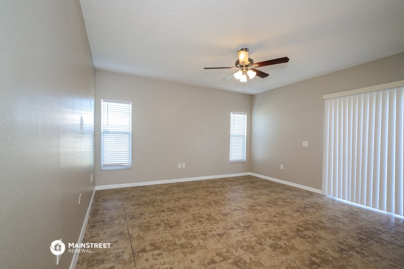 an empty living room with a ceiling fan and a large window