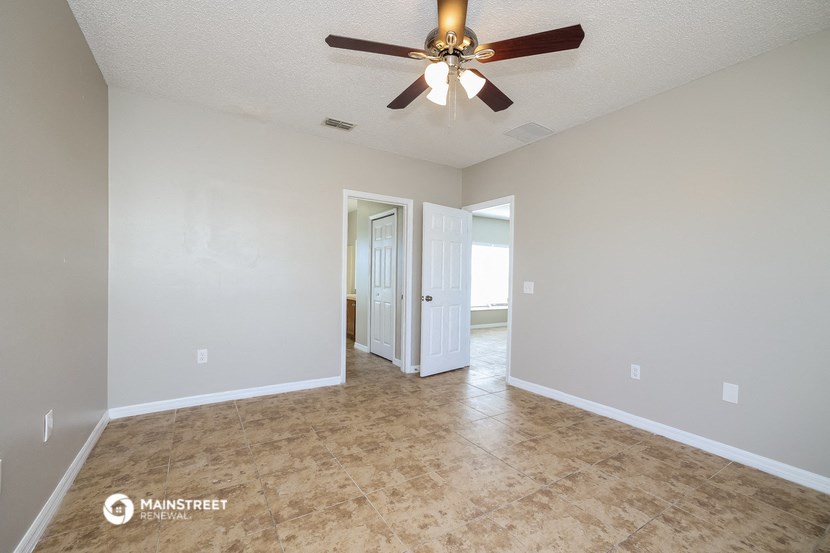 an empty living room with a ceiling fan and a door to a bathroom