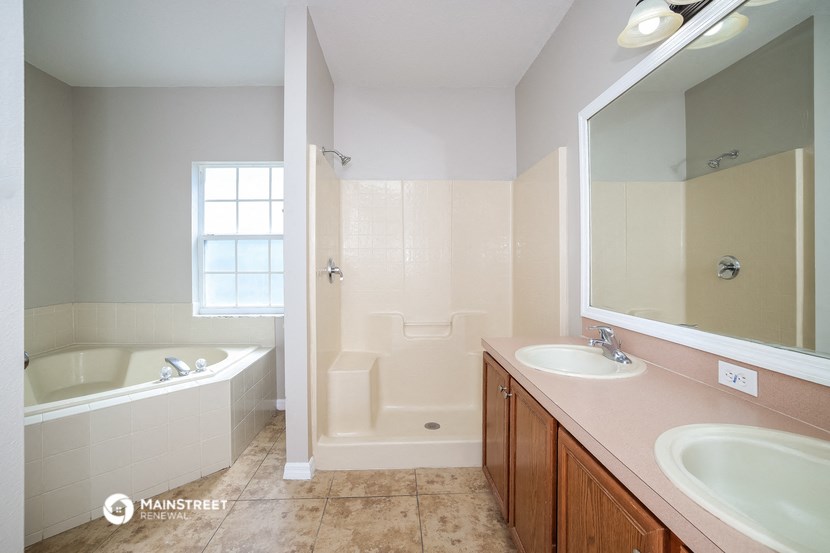 a bathroom with two sinks and a tub and a mirror