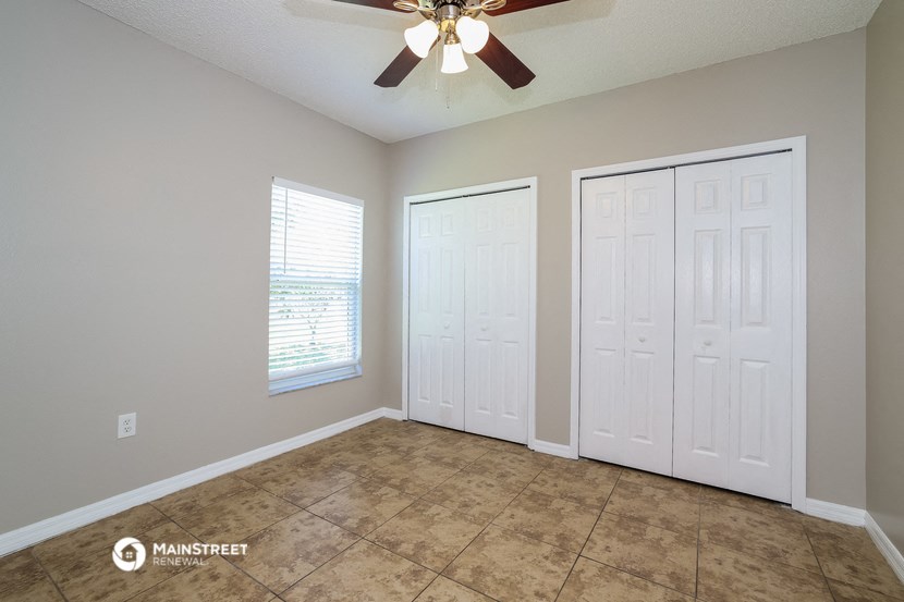 the spacious living room with two closets and a ceiling fan