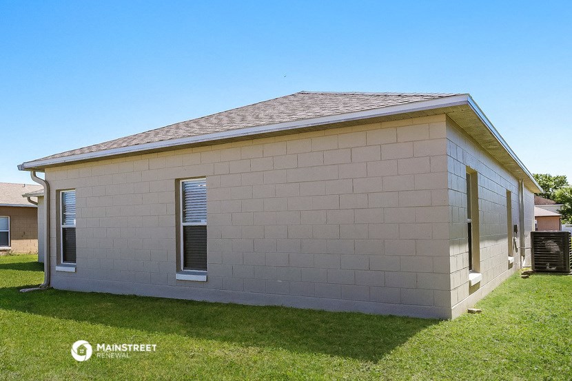 a small tan brick house with two windows on the side