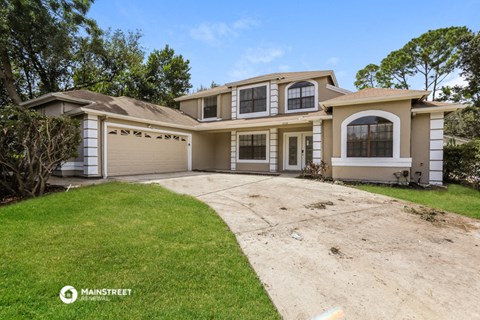 a beige house with a driveway and a lawn