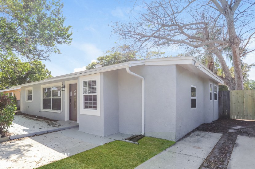 a white house with a sidewalk and a tree