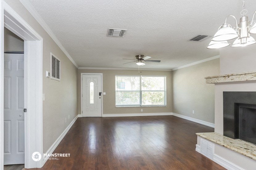an empty living room with a fireplace and a ceiling fan
