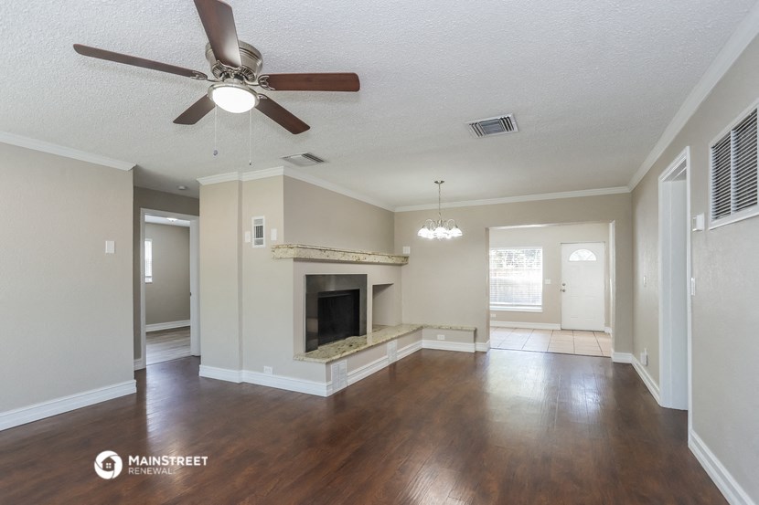 an empty living room with a ceiling fan and a fireplace