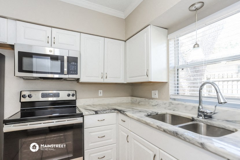 a kitchen with white cabinets and a sink and a microwave