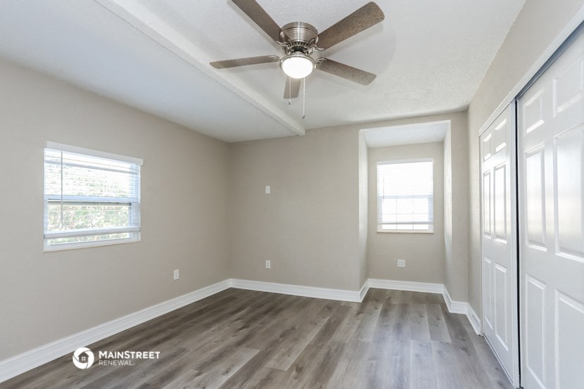 the spacious living room has a ceiling fan and wood flooring
