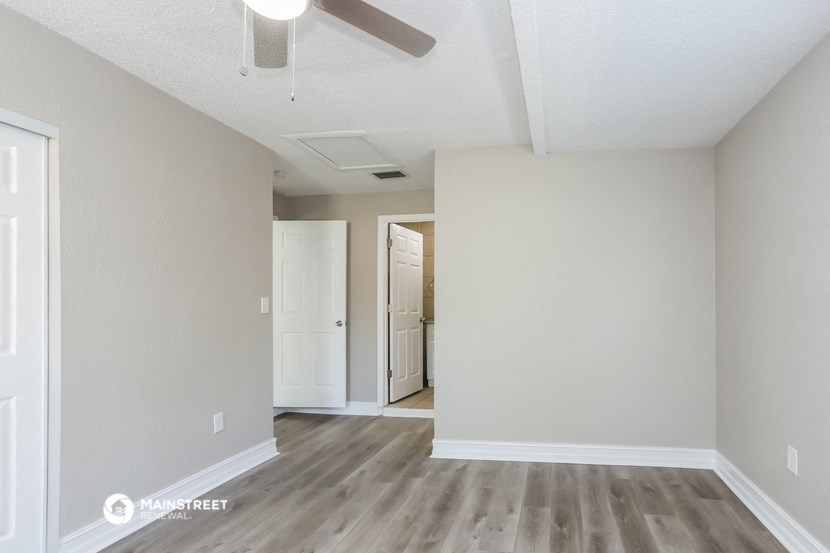 an empty living room with wood flooring and a ceiling fan