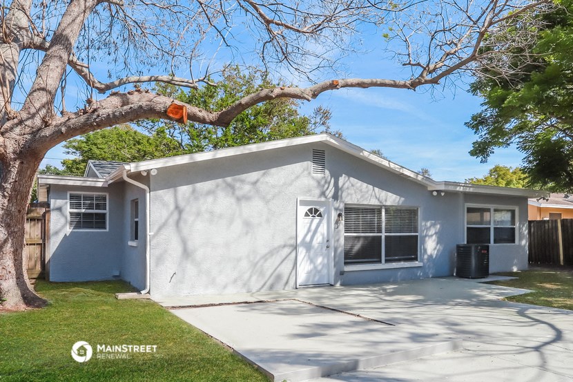 a white house with a tree and a driveway