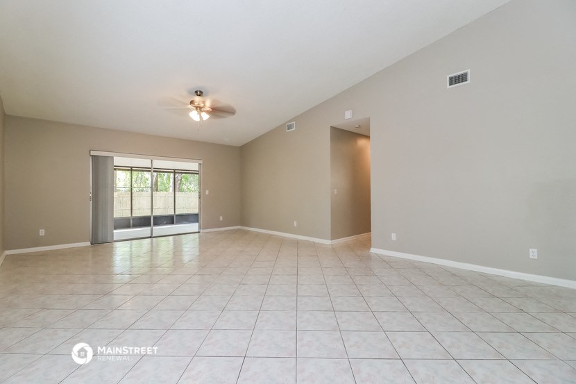 the spacious living room with tile flooring and a ceiling fan