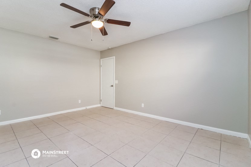 the spacious living room with ceiling fan and tile flooring