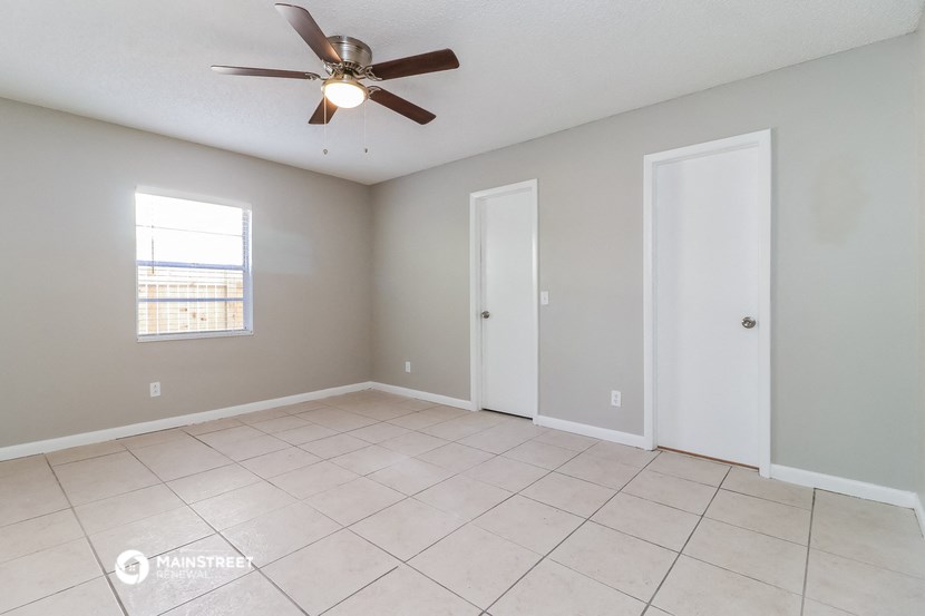 the spacious living room with ceiling fan and tiled floor