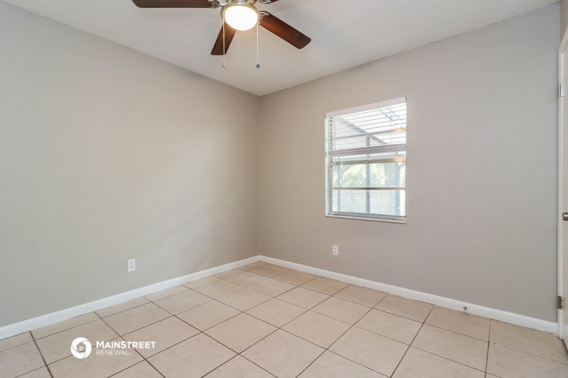 the living room of an empty home with a ceiling fan
