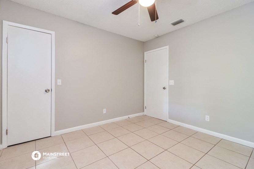 a empty living room with a ceiling fan and a tiled floor