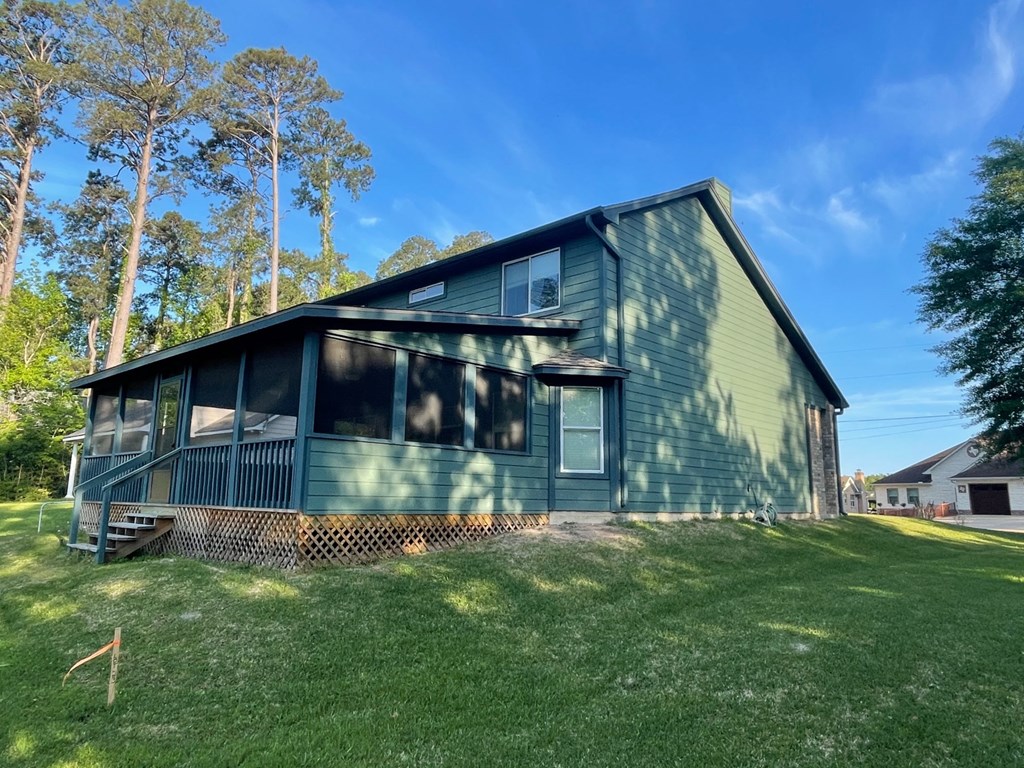 the front of a green house with trees in the background