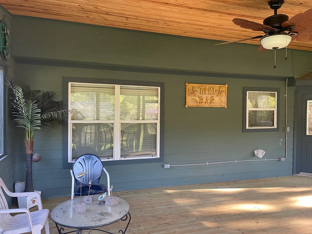 the screened in porch has a table and chairs and a ceiling fan