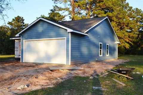 A blue house with a white garage door is under construction.