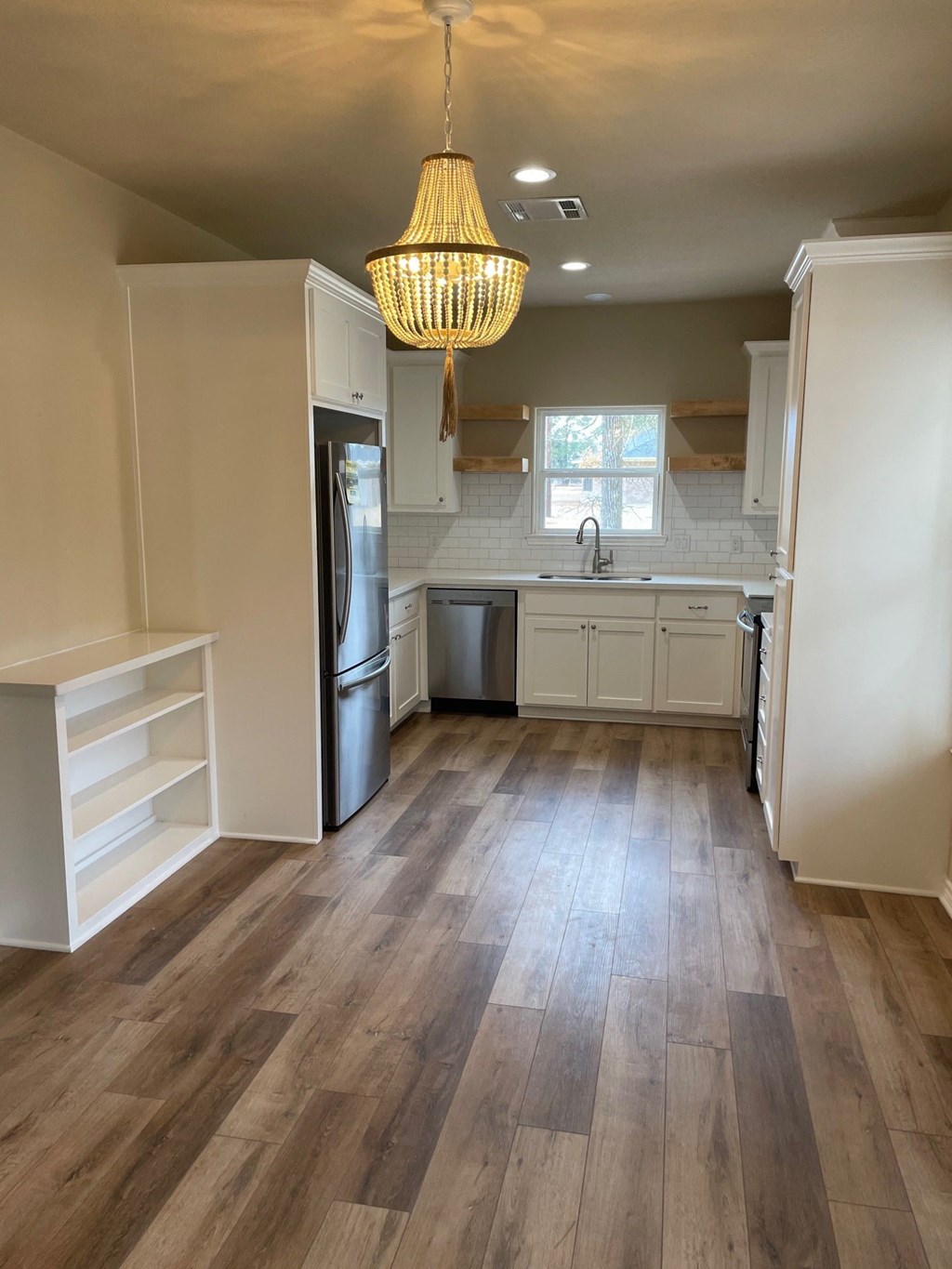 A kitchen with white cabinets and a wooden floor.