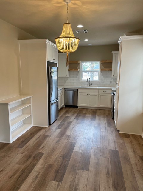 A kitchen with white cabinets and a wooden floor.