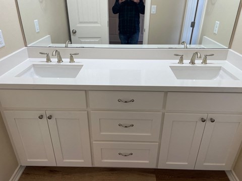 A bathroom with two sinks and white cabinets.