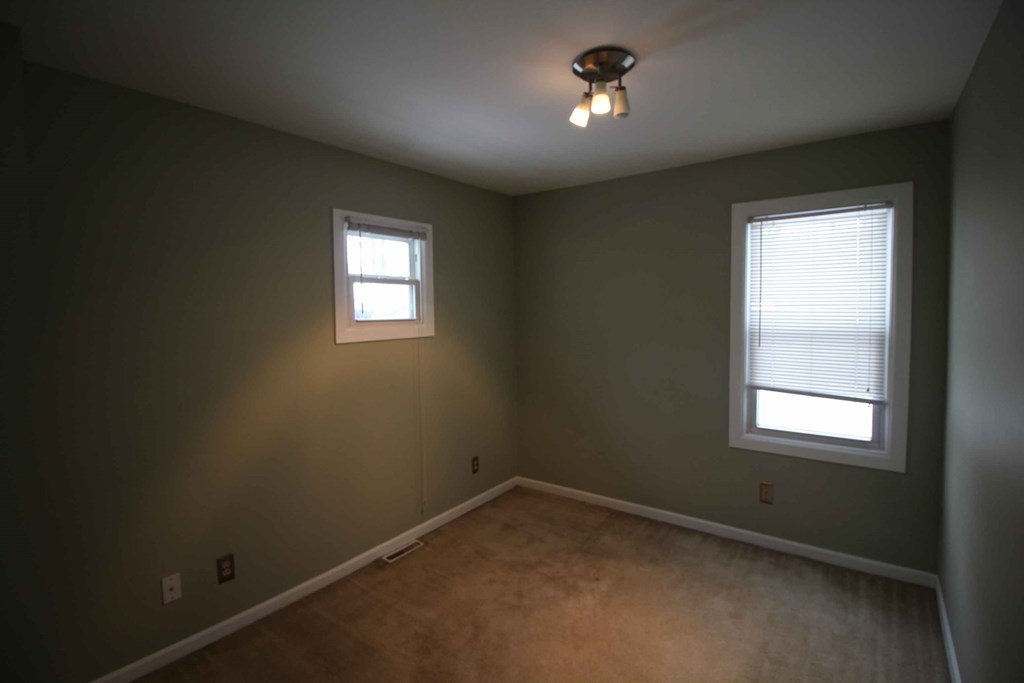 a empty room with a ceiling fan and two windows