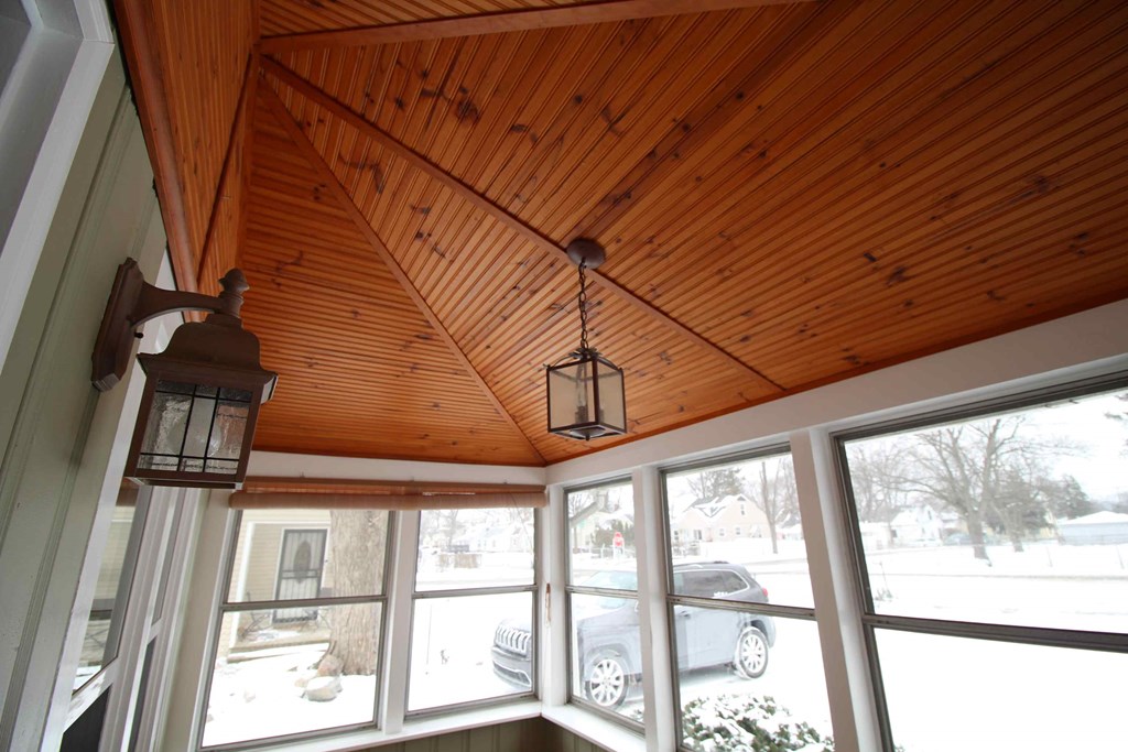 the screened porch has large windows and a wood ceiling