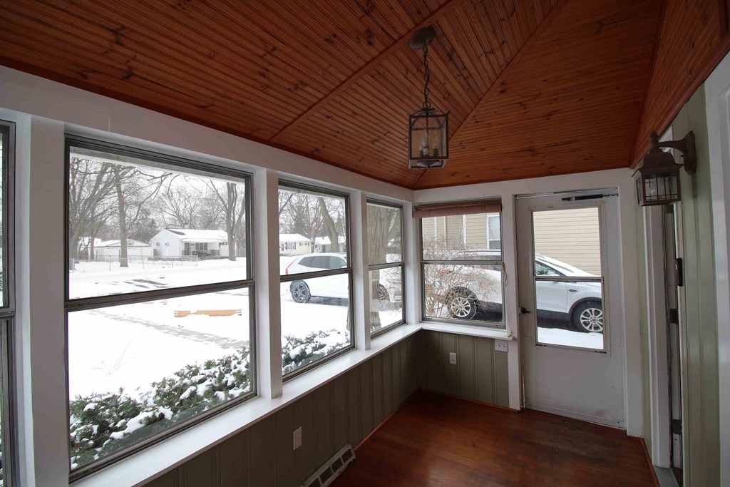 a view of the front porch with large windows and a wood ceiling