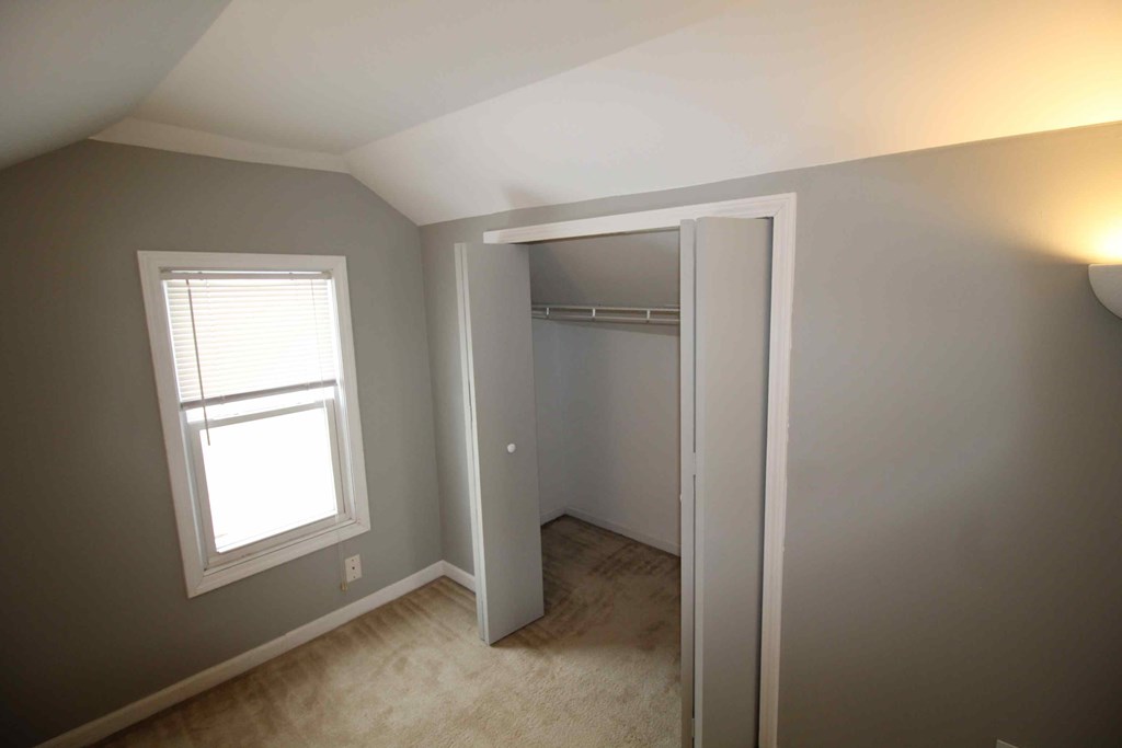 a bedroom with a closet and a window and a door to a closet