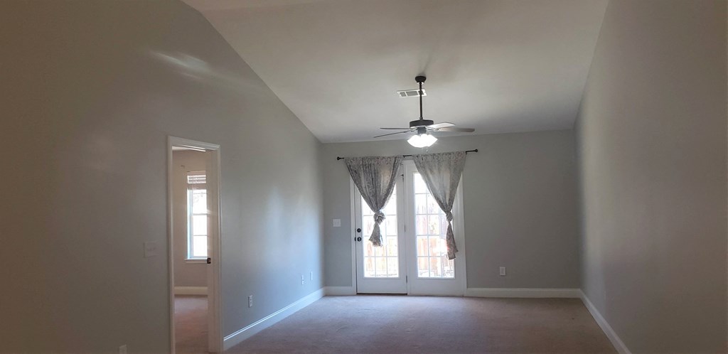 an empty living room with a ceiling fan and a window
