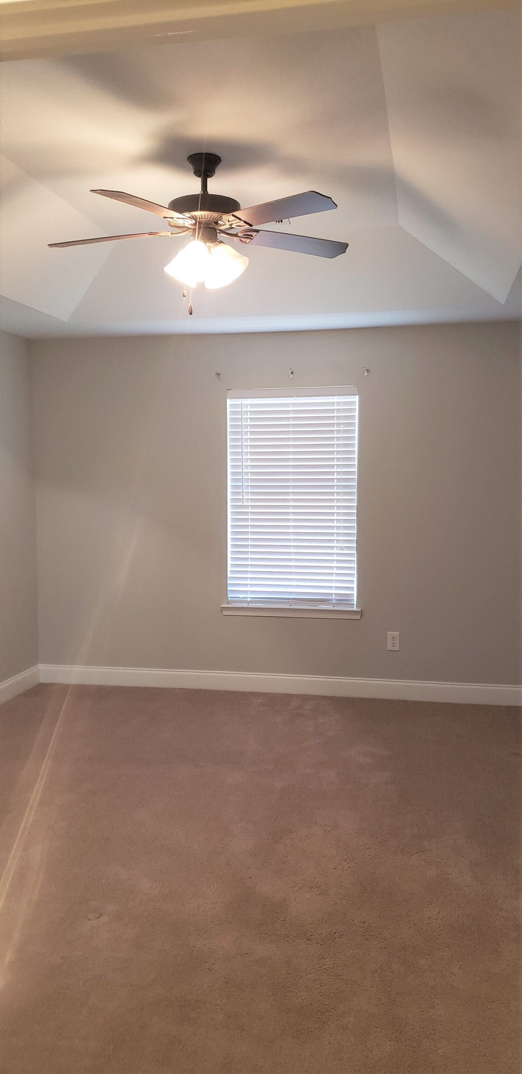 an empty room with a ceiling fan and a window