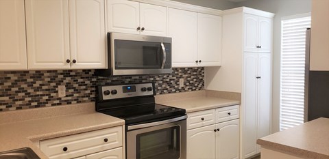 a kitchen with white cabinets and a stove and a microwave