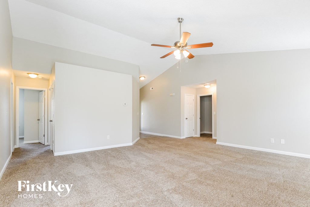 a spacious living room with white walls and a ceiling fan