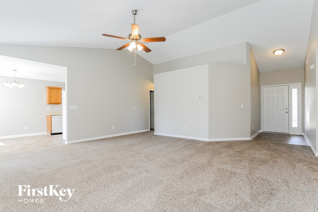 the spacious living room with ceiling fan and carpeting