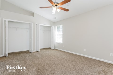 a bedroom with white walls and carpet and a ceiling fan
