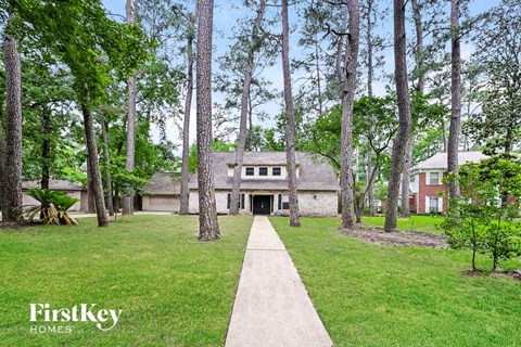 a house in the middle of a yard with tall trees