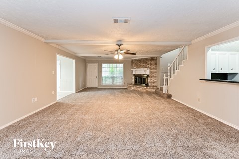an empty living room with a ceiling fan and a fireplace