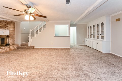 an empty living room with a fireplace and a ceiling fan
