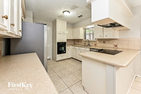 a kitchen with white cabinets and a black refrigerator