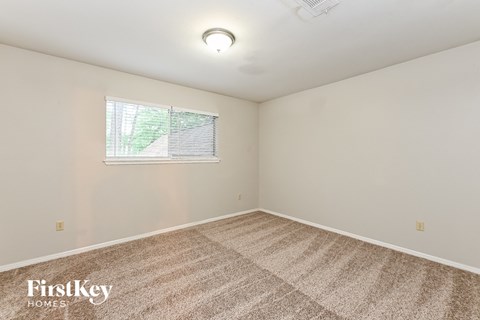 the living room is spacious and clean with carpet and a window
