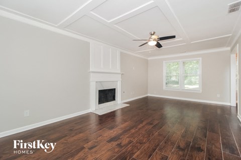an empty living room with a fireplace and a ceiling fan