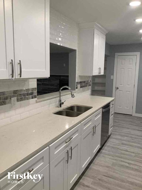 a white kitchen with a sink and white cabinets