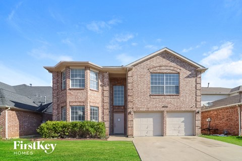 a brick house with two garage doors and a lawn