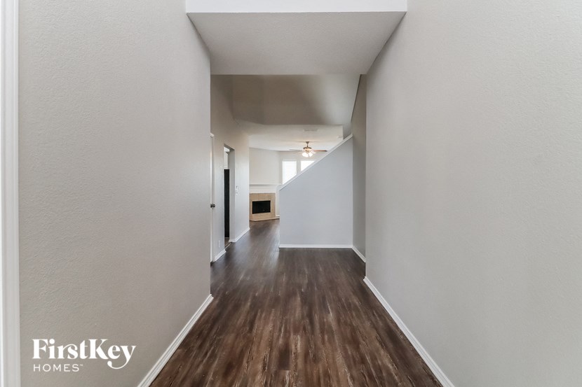 the living room and hallway of an apartment with wood flooring and white walls