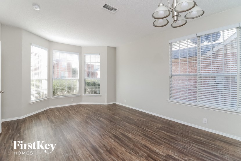 the living room of an empty house with wood flooring and windows