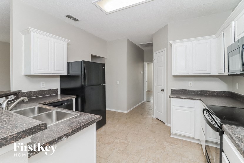 a kitchen with white cabinets and black appliances