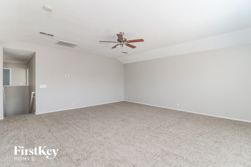an empty living room with a ceiling fan
